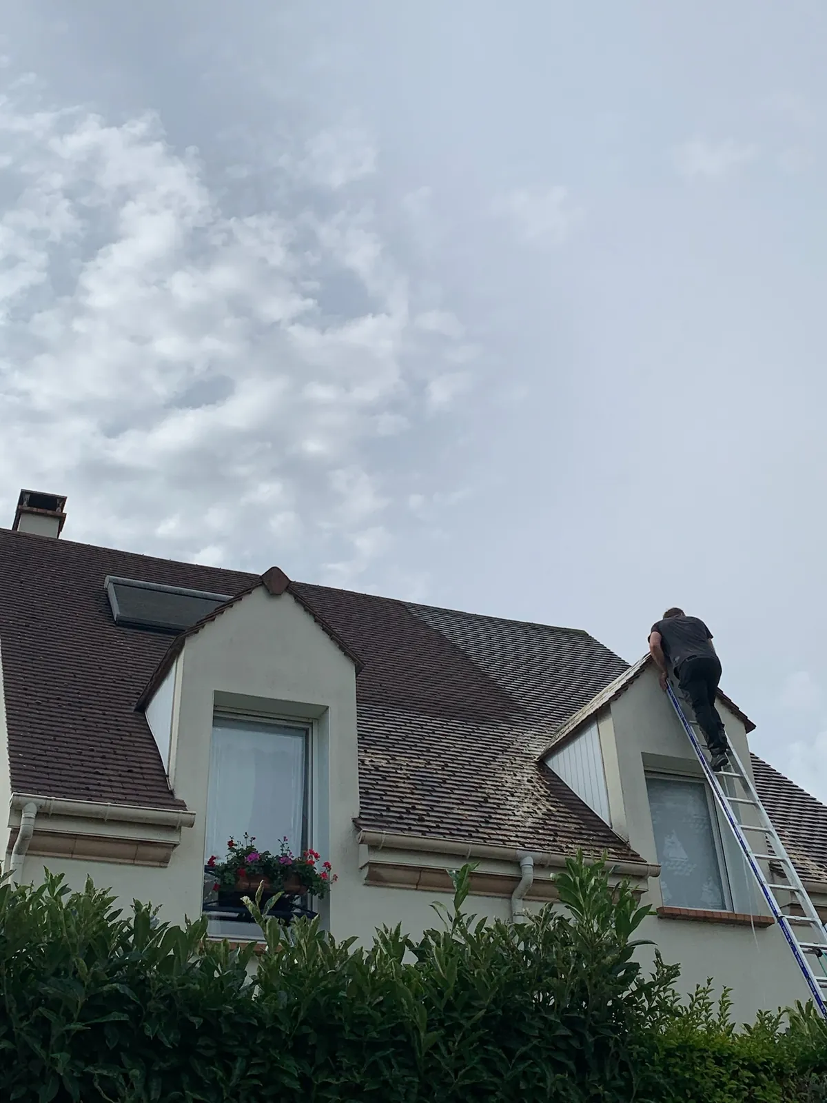 Couvreur sur une échelle, à la recherche d'une fuite sur la toiture d'un pavillon — M. Simonard, couvreur en Seine-et-Marne