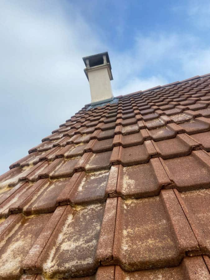Vue sur une toiture, en tuile, qui salit avec des traces de pollution, qui nécessite un véritable nettoyage